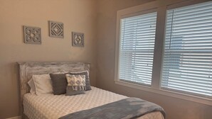 Un dormitorio con cama, ventana con persianas y decoración en la pared.