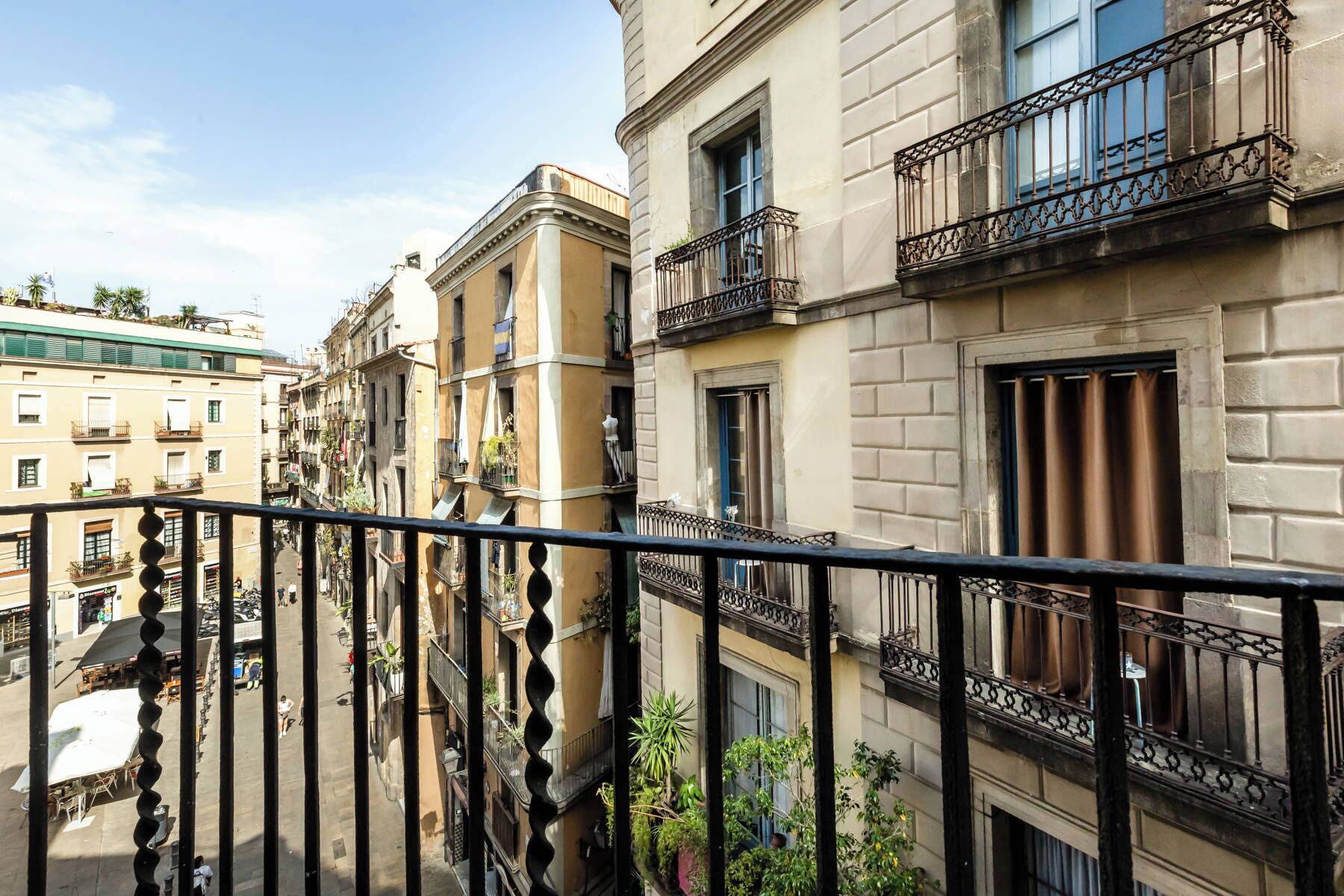 A multi-story building with balconies, a street below, and a clear sky.