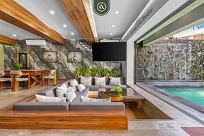 A modern lounge area with a stone wall, a pool, and a seating area with cushions and a coffee table. - 4BR B-nayar Brisas 116 Mountain Views, Pool (Bucerías)