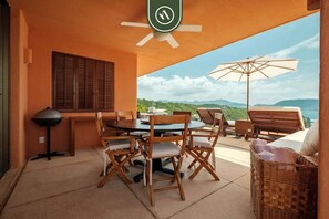 An outdoor patio with a round table, wooden chairs, a ceiling fan, and a view of the landscape. - 4 BR Penthouse - Breathtaking Views - Private Pool (Ixtapa)