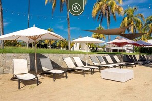 A beachside lounge area with sun loungers, umbrellas, and a stone wall. - B Nayar 3BR Sanctuary: Private Balcony, Full Kitchen & Steps to La Cruz Marina (La Cruz de Huanacaxtle)