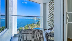 Ein Balkon mit Korbmöbeln, Blick auf das Meer und die Stadtlandschaft.