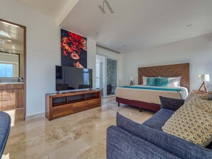 Ein modernes Schlafzimmer mit einem großen Bett, einem Fernseher auf einem Holzboden und einer Glastür zum Balkon.