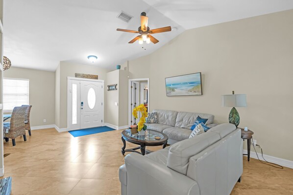 A living room with a grey sofa, a coffee table, and a ceiling fan.