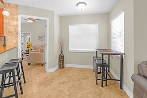 A modern kitchen with a wooden countertop, bar stools, and a dining area with a table and chairs.