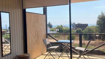 Ein modernes Interieur mit Holzboden, einer großen Schiebeglas-Tür, die auf eine Terrasse führt, und einem Tisch mit zwei runden Untersetzern.