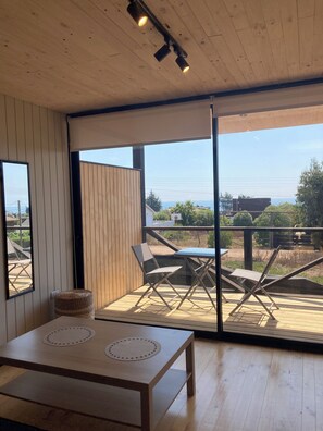 A modern interior with a wooden ceiling, a large sliding glass door leading to an outdoor deck, and a table with two circular mats.