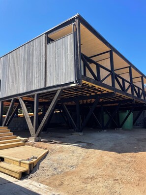 A construction site with a partially built structure featuring a wooden exterior and a metal framework.