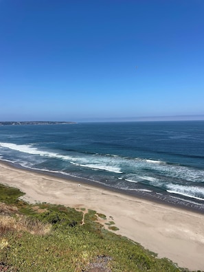 A beach with waves, a clear sky, and distant land. - Alba Lodge (Puchuncavi)