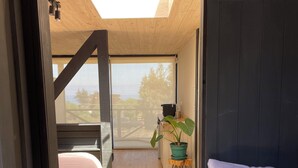 A room with a skylight, a bed, a bench, a potted plant, and a view of the outdoors. - Alba Lodge (Valparaíso)
