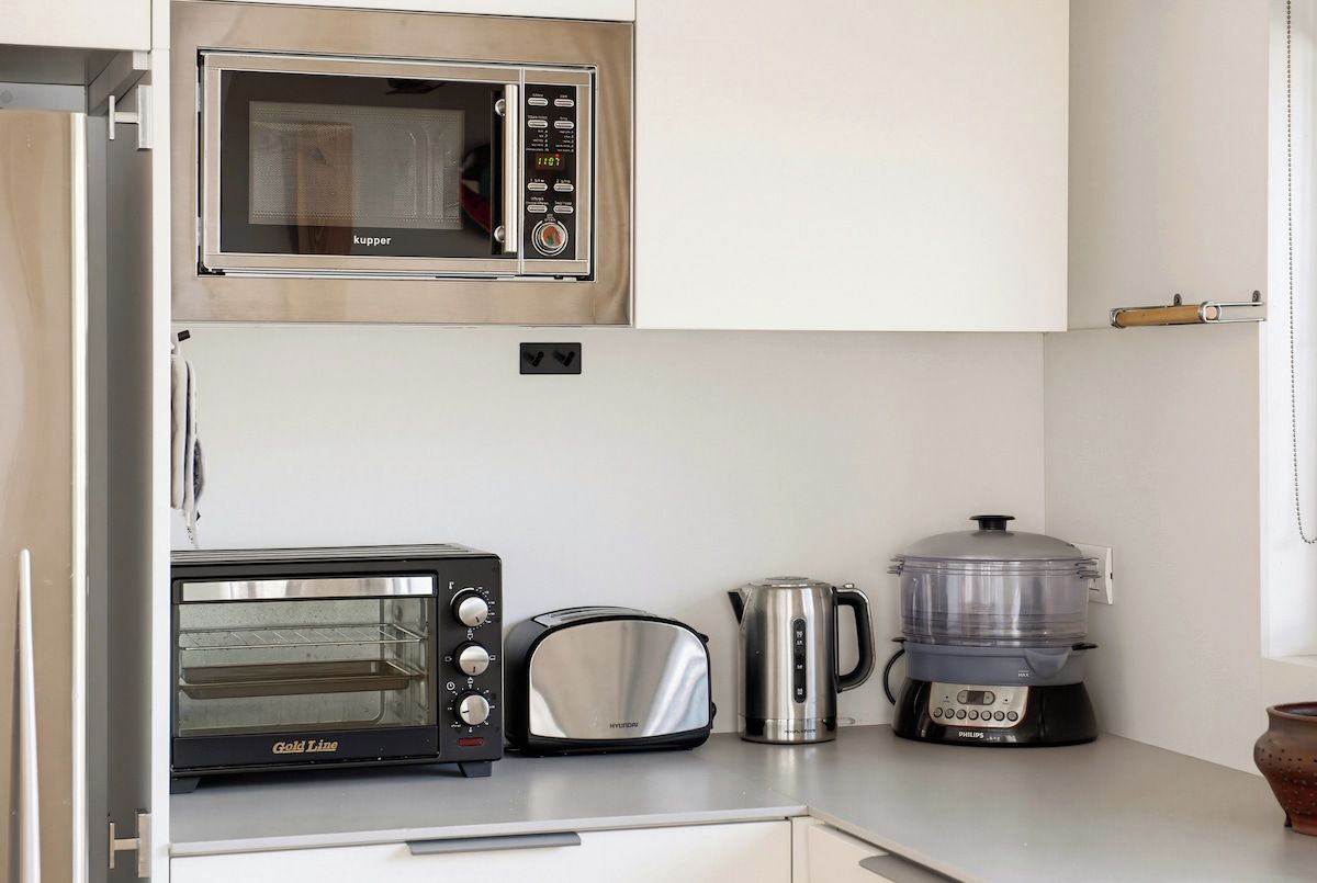 A kitchen with a microwave, toaster, kettle, and slow cooker.