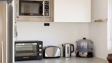 A kitchen with a microwave, toaster, kettle, and slow cooker.