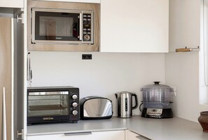 A kitchen with a microwave, toaster, kettle, and slow cooker.