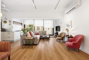 A modern living room with a sofa, armchairs, a coffee table, and a dining area.