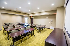 A conference room with multiple tables and chairs, carpeted flooring, and recessed ceiling lights.