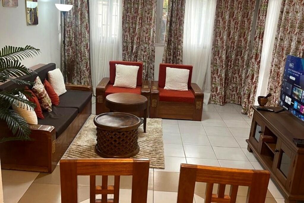 Ein Wohnzimmer mit einer Couch, zwei Sesseln, einem Couchtisch und einem Fernseher.