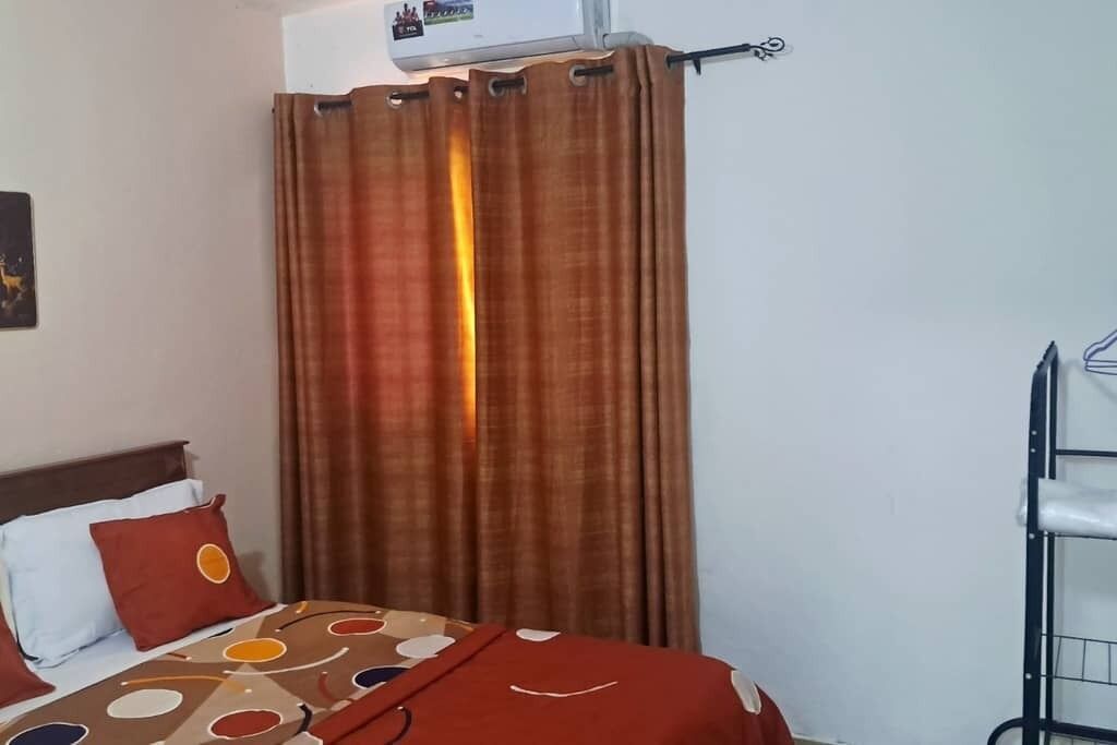 Ein Hotelzimmer mit einem Bett, einem Vorhang, einer Klimaanlage und einem Metallregal.