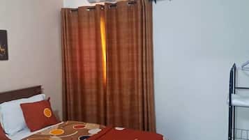Ein Hotelzimmer mit einem Bett, einem Vorhang, einer Klimaanlage und einem Metallregal.