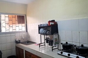 A kitchen with a gas stove, a sink, and a window with bars.