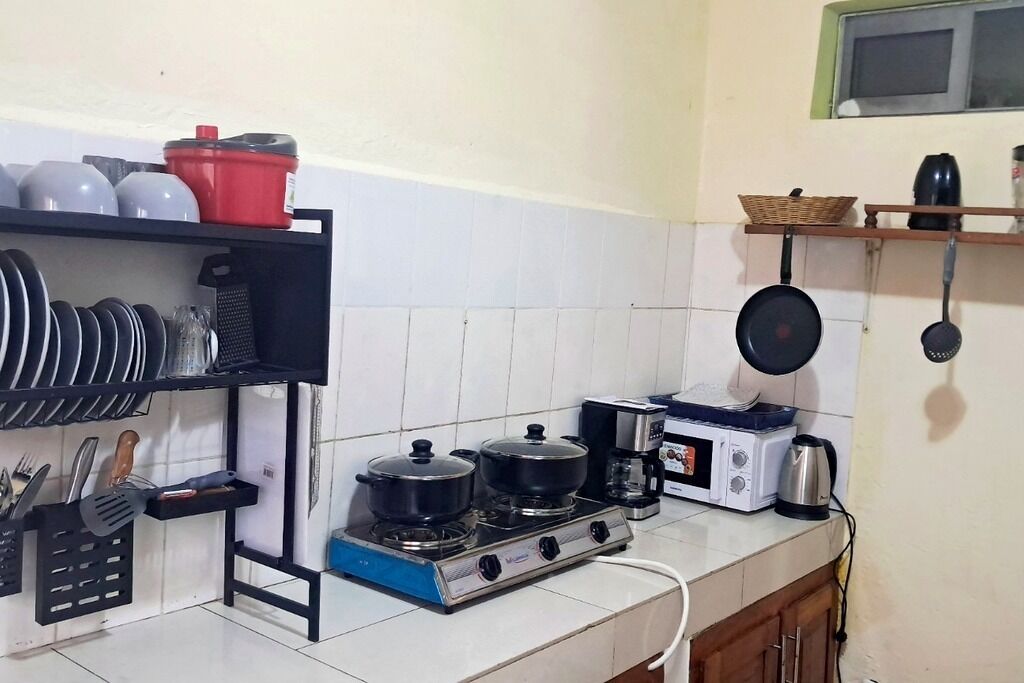 A kitchen with a gas stove, microwave, and various utensils.