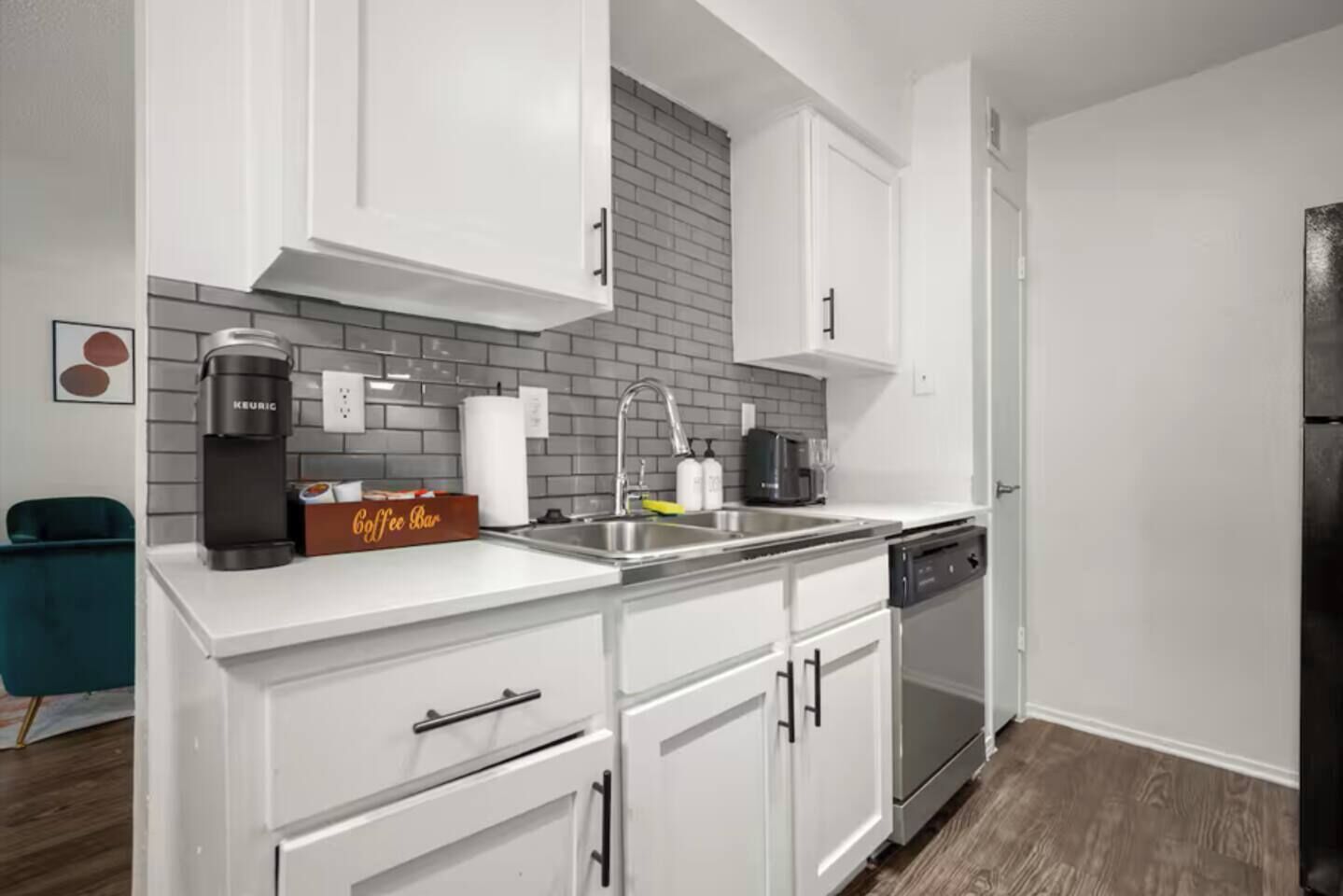 A modern kitchen with white cabinets, a coffee maker, a sink, and a dishwasher.