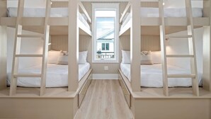Ein Zimmer mit Etagenbetten, einem Fenster und Blick auf ein Gebäude.