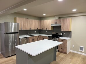 A modern kitchen with a stainless steel refrigerator, a built-in oven, and wooden cabinets.