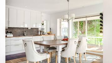 A modern kitchen with white cabinets, a wooden dining table, and four upholstered chairs.