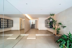 Eine moderne Lobby mit Glaswand, einer Treppe und einer Zimmerpflanze.
