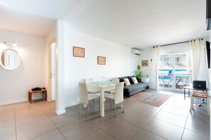 A modern living room with a dining area, a sofa, and a balcony with a pool view. - Le Palm Beach aperçu mer avec balcon proche plages (Cannes)