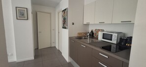Eine Küche mit Mikrowelle, Toaster und Spüle. Eine Tür führt in einen anderen Raum.