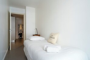 Ein Hotelzimmer mit Bett, Kissen, Nachttisch und einer Tür zu einem anderen Raum.