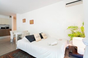 A hotel room with a bed, a desk, a chair, a small table, a plant, and a window. - Le Palm Beach aperçu mer avec balcon proche plages (Cannes)