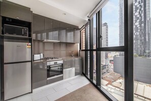 Une cuisine moderne équipée d’appareils électroménagers en acier inoxydable, d’une cuisinière à gaz et offrant une vue sur la ville grâce à de grandes fenêtres.