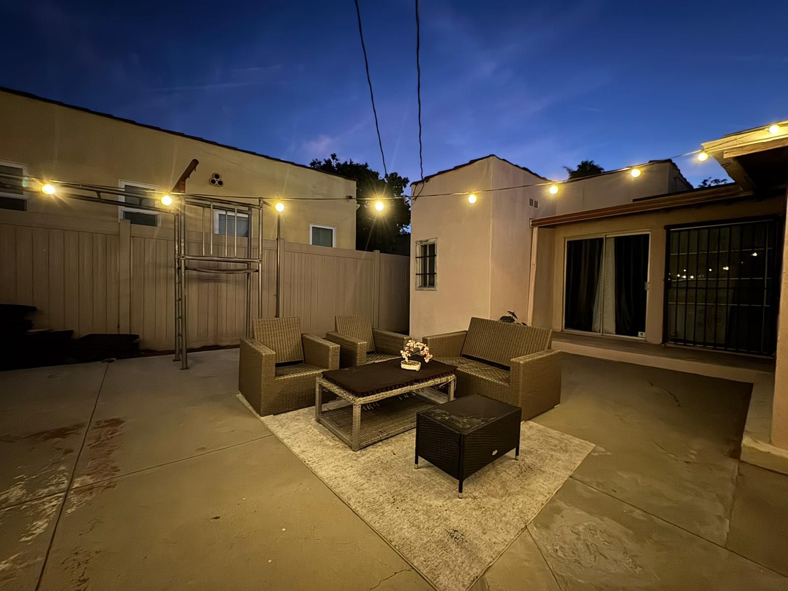 An outdoor patio area with a seating arrangement, a small table, and string lights.