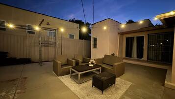 An outdoor patio area with a seating arrangement, a small table, and string lights.