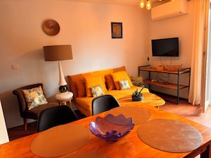 A modern living room with a sofa, a dining table, a TV, and a lamp.