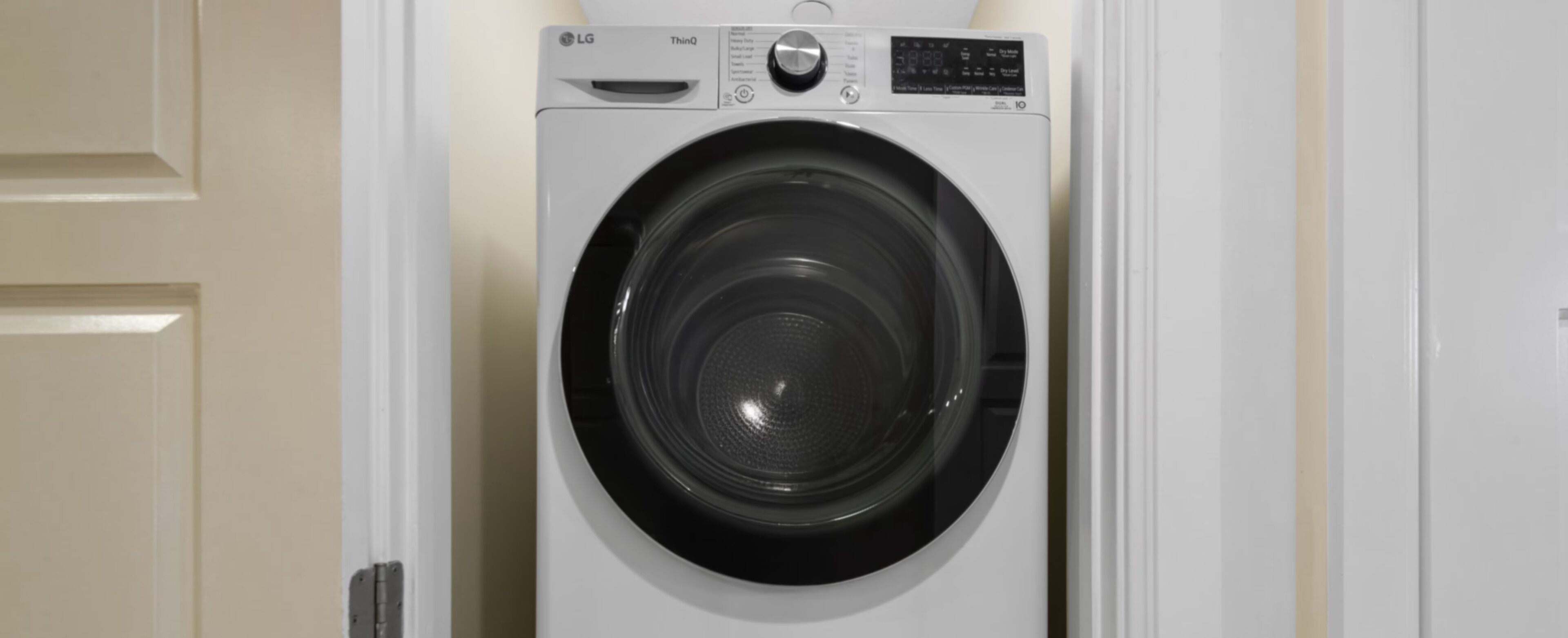 A front-loading LG ThinQ washing machine with a control panel and a digital display.