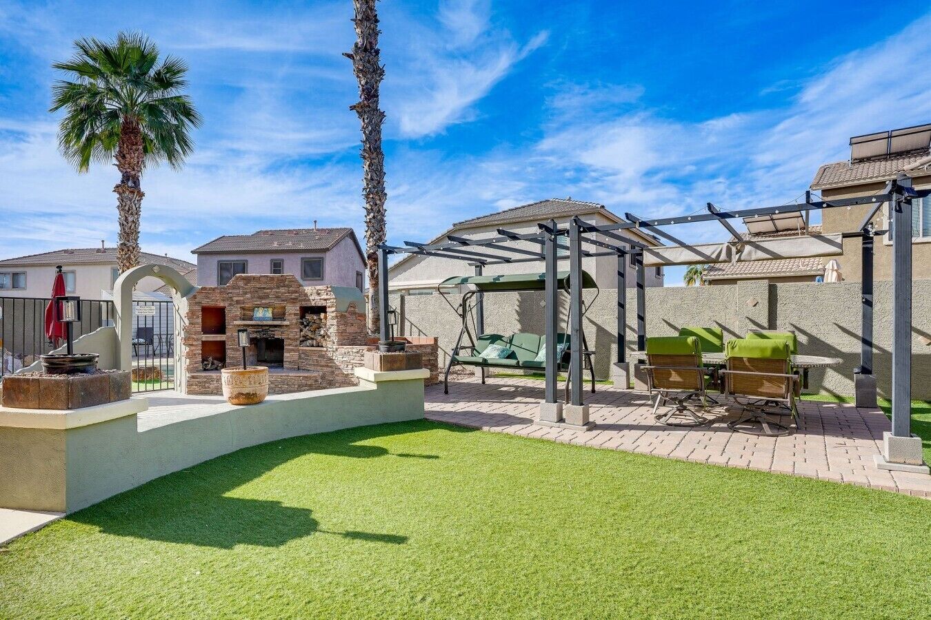 A backyard with a barbecue area, outdoor seating, and a stone fireplace.