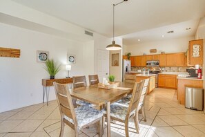 A modern kitchen with wooden cabinets, a stainless steel refrigerator, and a dining area with a wooden table and chairs. - The Surprise Oasis, Heated Pool, Pet Friendly (Surprise)
