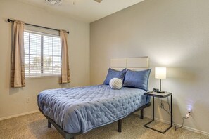 A bedroom with a bed, a bedside table with a lamp, and a window with curtains. - The Surprise Oasis, Heated Pool, Pet Friendly (Surprise)