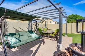 A covered patio area with a green sofa, a table, and chairs. - The Surprise Oasis, Heated Pool, Pet Friendly (Surprise)
