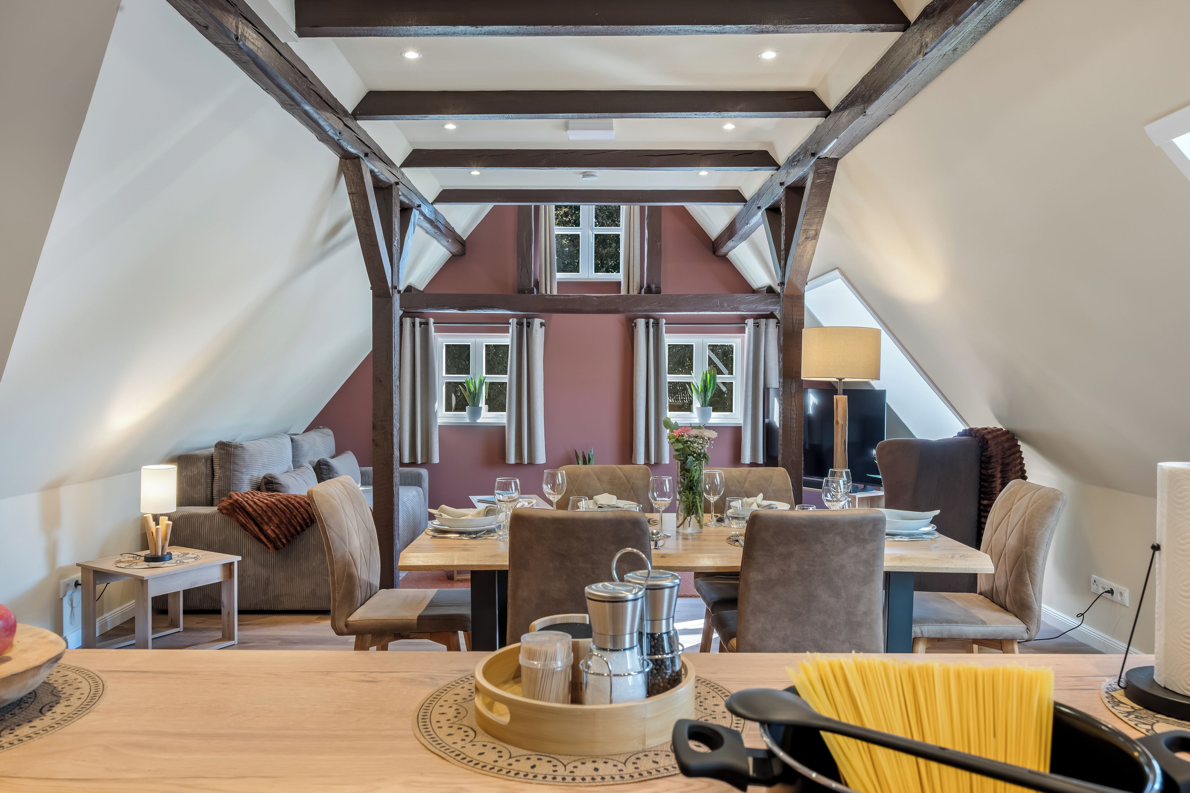 Ein Essbereich mit Tisch für zwei Personen, einer Couch und einem Fenster mit Vorhängen.