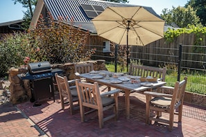 An outdoor patio with a dining table, chairs, a grill, and a large umbrella. - Heidschnucke Vacation Rental – 110 m² with a sauna for families and dogs in the Lüneburg Heath (Wriedel)