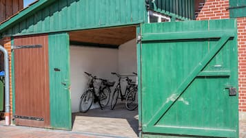 Ein grünes Metalltor, dahinter ein Fahrrad, das in einem Gebäude abgestellt ist.