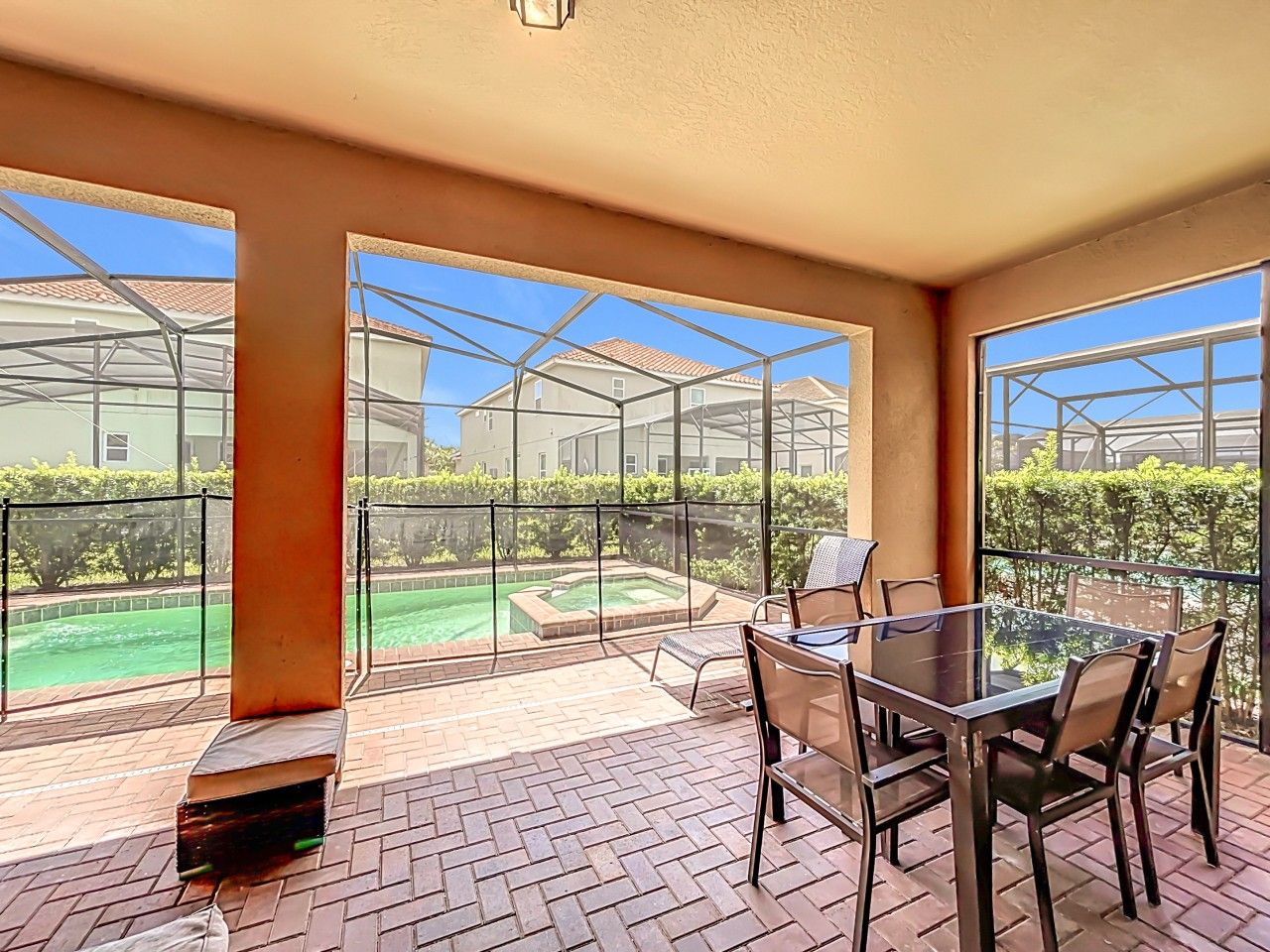 A spacious balcony with a glass table and chairs, overlooking a swimming pool and greenery.