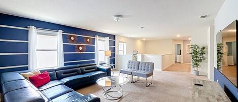 Una sala moderna con un sofá modular, una mesita redonda y un sillón gris.