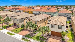 A residential area with multiple houses featuring red-tiled roofs, well-maintained lawns, and palm trees. - 7BR Solterra Resort Themed Home, Games, Fun,Disney (Davenport)