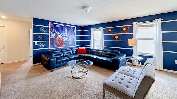 A living room with a sectional sofa, a round coffee table, and a tufted ottoman. - 7BR Solterra Resort Themed Home, Games, Fun,Disney (Davenport)