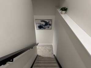 A staircase with a handrail, a wall-mounted plant, and a framed abstract painting. - Paradise in Glenridding (Edmonton)